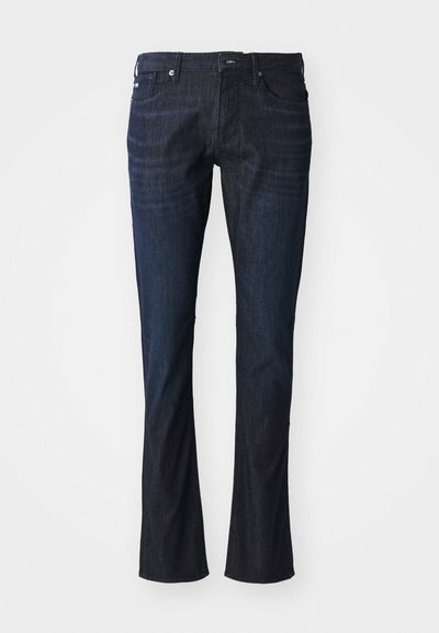 Mørkeblå denimjeans med rett ben, fem lommer, knappelukking og lett falming på lårene. Flat kant og ingen synlige mønstre.