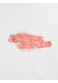 Λευκό ύφασμα με το κείμενο "JACK & JONES" σε έντονους γράμματα με περίγραμμα πάνω σε ακανόνιστο κόκκινο φόντο από πιτσιλιές μπογιάς.