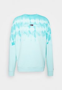 Jasnoniebieska bluza tie-dye z okrągłym kołnierzem, długimi rękawami i haftowanym logo "TOMMY JEANS" na plecach.