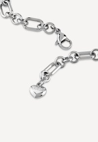 Bracciale in argento con grandi anelli intrecciati, dotato di chiusura a gancio e di un ciondolo a forma di cuore inciso con "GUESS".