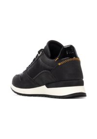 Zapatilla deportiva negra que presenta una mezcla de cuero texturizado y ante, una entresuela blanca y un detalle de costura naranja en el talón.