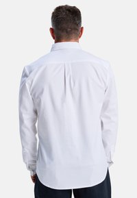 Weißes, langärmliges Hemd mit klassischem Kragen, Mittelnaht und abgerundetem Saum. Hergestellt aus glattem Stoff mit geknöpften Manschetten.