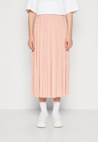 Pleated midi-hame pehmeässä vaaleanpunaisessa, kevyessä kankaassa, joustovyöllä. Yhdistetty valkoisten lenkkareiden ja nilkkasukkien kanssa.