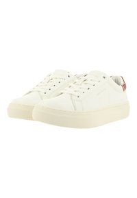 Witte canvas sneakers met een textuurafwerking, ronde neus, vetersluiting en een rode accenten op de hak. Dikke rubberen zool, minimalistisch ontwerp.