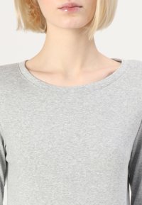 Siva majica dugih rukava sa širokim, zaobljenim izrezom; mekani materijal; minimalistički dizajn, usmjeren na ležeran, udoban kroj.