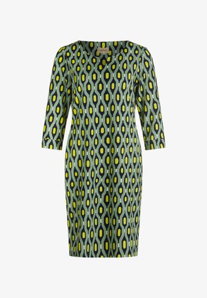 Jurk met een groene basis en een geometrisch patroon in marineblauw, geel en wit. Heeft een V-hals en driekwart mouwen.
