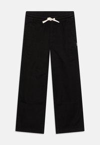 Pantalons larges noirs en coton avec une taille élastique et un cordon blanc. Dispose de poches latérales et de coutures minimales.