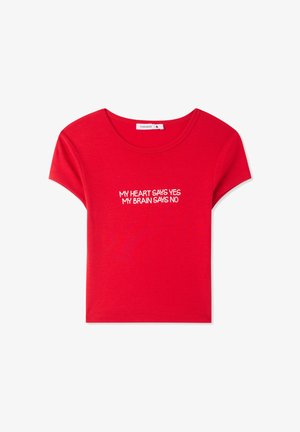 T-shirt rossa in cotone con maniche corte e scollatura rotonda, caratterizzata da un testo bianco che recita "IL MIO CUORE DICE SÌ, IL MIO CERVELLO DICE NO."