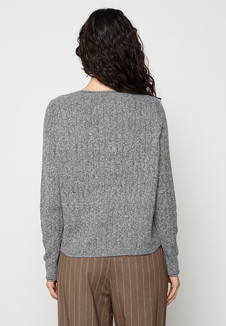Grauer gestrickter Pullover mit langen Ärmeln, Rundhalsausschnitt und strukturiertem Finish. Geeignet für legere Outfits, kombiniert mit braunen gestreiften Hosen.