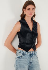 Námornícky pruhovaný bezrukávový sveter s výstrihom do V, so zakriveným spodným lemom a piatimi gombíkmi vpredu, doplnený o svetlomodré denimové šortky.