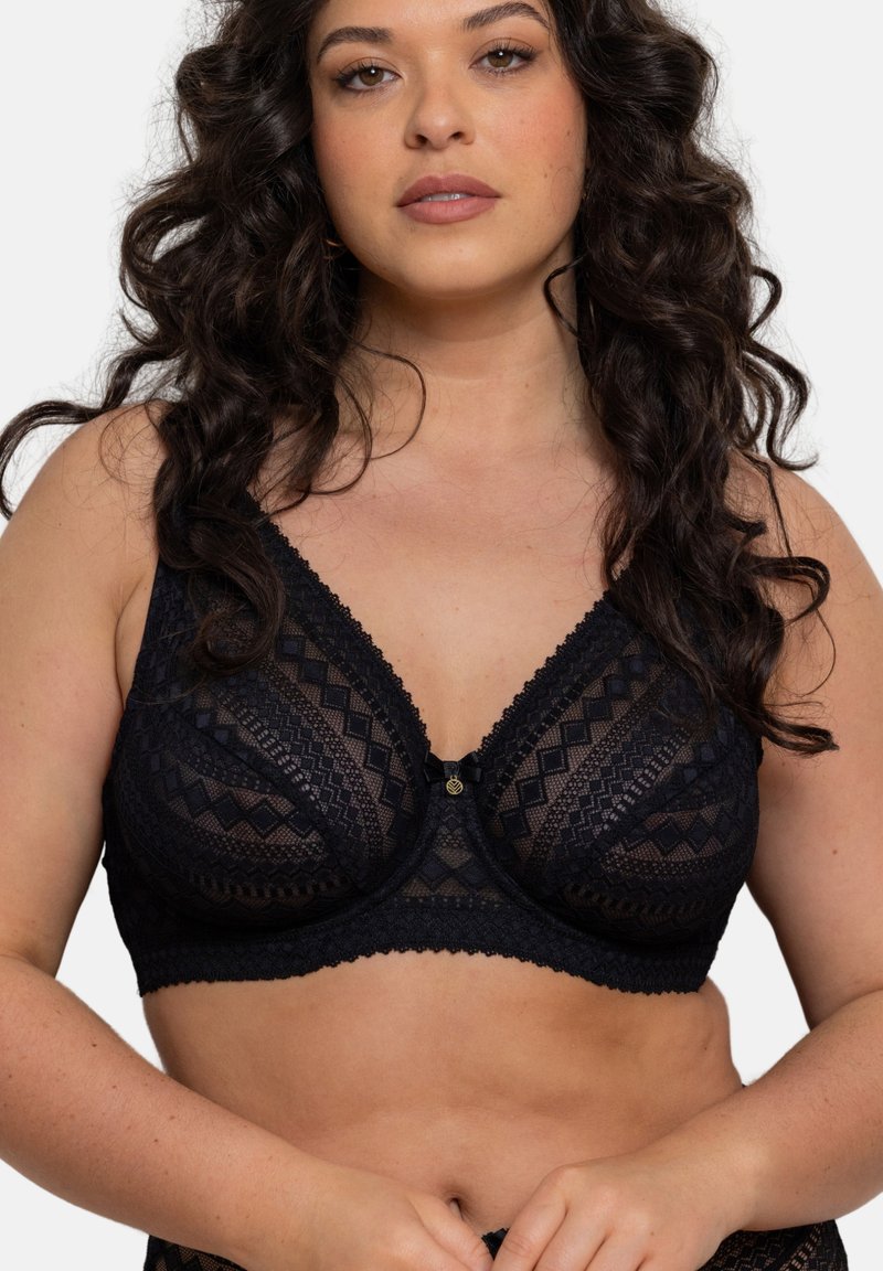 Soutien-gorge en dentelle noire présentant un motif géométrique, un soutien à armature et un petit détail décoratif central. Texture douce avec des finitions délicates.