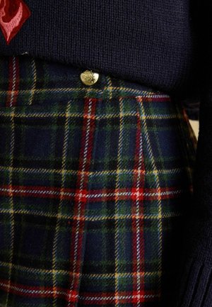 Merevaigukalpne meresinine kampsun kantud üle ruudulise seeliku, millel on rohelised, punased ja kollased toonid ning millel on kuldsed nupukirjeldused ja tekstureeritud villa kangas.