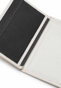 Weißes Leder-Wallet-Innenleben mit strukturiertem Finish, verfügt über einen schwarzen Stoffbereich, mehrere Kartensteckplätze und kontrastierende Nähte.