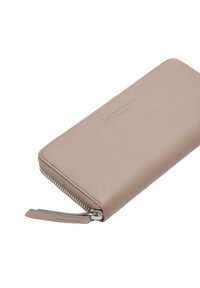 Jasnobeżowy skórzany portfel z zamknięciem na zamek, gładką fakturą, wytłoczonym logo i metalowym suwakiem. Kompaktowy, prostokątny kształt.