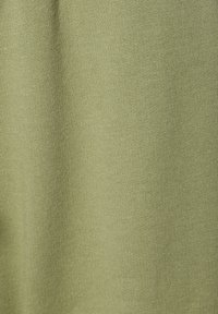 Groene gebreide stof met een gladde textuur, met een zachte, uniforme uitstraling en een gematigde rek. Geen patronen of hardware zichtbaar.