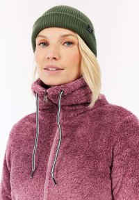 Ružová fleecová bunda s vysokým golierom a čiernymi zipsovými detailmi, spolu so zelenou rebrovanou čiapkou. Mäkká textúra, pohodlný dizajn.