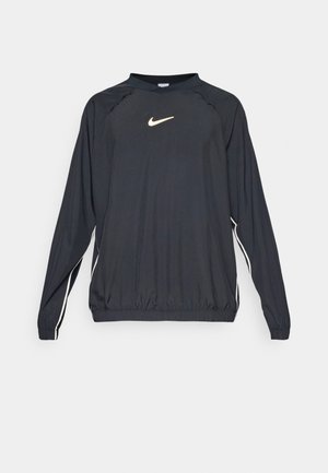 Schwarzer langärmeliger Pullover mit Rundhalsausschnitt, der ein goldenes Nike-Logo und weiße Seitenstreifen aufweist. Hergestellt aus leichtem, glattem Material.