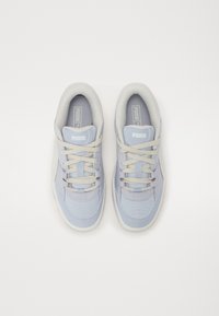 Baskets bleu clair avec une tige synthétique lisse, bout rond, lacets beige contrastants, col rembourré et semelle en caoutchouc texturée.