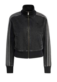 Crna traper jakna s visokim ovratnikom i prednjim patentnim zatvaračem. Ima bijele trostruke pruge na rukavima i rebraste manžete.