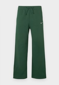 Tmavohnedé voľné tepláky so sťahovacím pásom a malým bielym logom Nike na ľavom stehne na jednoduchej pozadí.