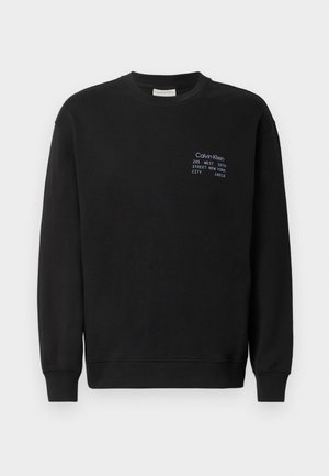 Svart bomullsgenser med lange ermer, rund hals og ribbestrikkede mansjetter. Har brodert merke i blått på brystet.