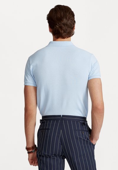 Light blue polo shirt with short sleeves, textured fabric, and collar, paired with navy pinstriped trousers featuring side pockets.