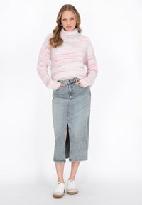 Maglione a collo alto a strisce rosa e bianche abbinato a una gonna di jeans in vita alta con uno spacco frontale e sneakers bianche.