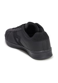 Scarpa sportiva nera con una tomaia sintetica liscia, suola in gomma testurizzata e design con lacci; presenta accenti sottili sui lati.