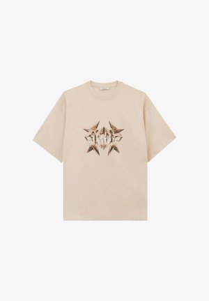 T-shirt beige a maniche corte con un motivo grafico metallico a forma di stella che ricorda le lettere "GCDS" al centro del petto.