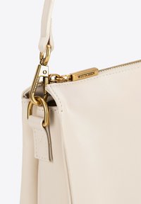 Borsa a mano in pelle beige chiaro con chiusura e zip in metallo dorato, con cuciture visibili e un'etichetta con logo.