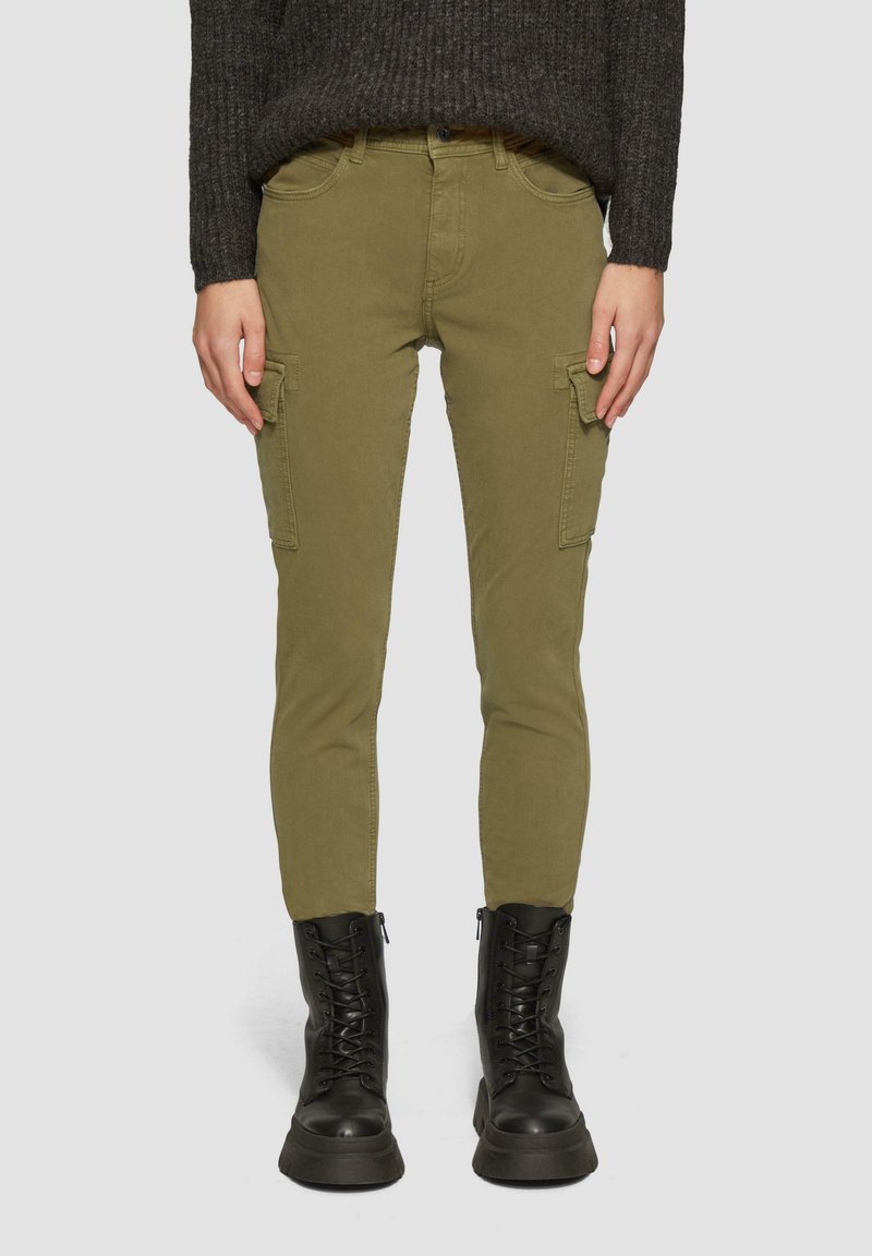 Cargo-broek in olijfgroene stof, met zijzakken, slim fit en versterkte stiksels. Gecombineerd met zwarte veterschoenen voor in de strijd.
