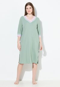 Camicia da notte verde chiaro con scollo a V e maniche a tre quarti, caratterizzata da accenti a righe rosa e bianche, fessure laterali e una morbida texture del tessuto.