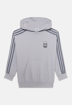 Siva kapuca s sprednjim žepom, nastavljivo kapuco z vrvico, tremi temno sivimi črtami na rokavih in logotipom na prsih. Mehka, teksturirana tkanina.