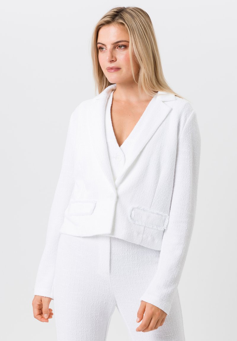 Weißes, tailliertes Blazer mit einem strukturierten Boucle-Stoff, ausgestattet mit Reverskragen, zwei Fronttaschen und einem einzelnen Knopfverschluss.
