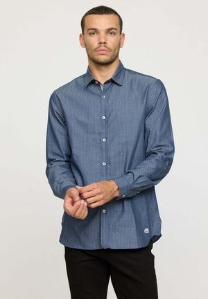 Chemise à manches longues pour hommes en bleu foncé avec un motif discret à pois, fermeture à boutons sur le devant et une coupe ajustée. Matière en mélange de coton avec une texture lisse.