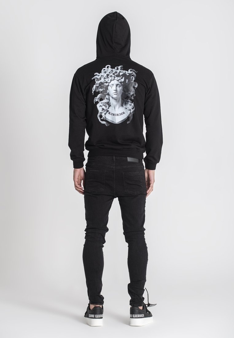 Crni dukserica s grafičkim printom koji prikazuje poprsje i lepršavu kosu na leđima. U kombinaciji s crnim uskim farmerkama i kontrastnim tenisicama.