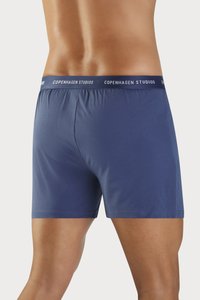 Marineblå boksershorts laget av glatt stoff, med en myk elastisk midjebånd som har "COPENHAGEN STUDIOS" trykt i hvitt.