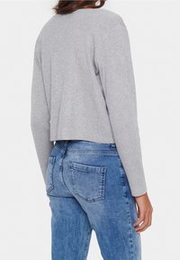 Grå ribbad kortärmad tröja med långa ärmar, kombinerad med ljusblå denimjeans med bakfickor och en urtvättad finish.