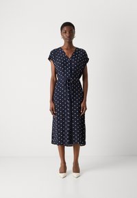 Navy blue dress with white polka dots, short sleeves, V-neck, adjustable waist tie, knee-length, lightweight fabric, side slits.