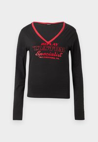 Schwarzes Langarmshirt mit V-Ausschnitt, rotem Kragenbesatz und auffälligem roten Drucktext mit der Aufschrift "REPLAY CUSTOM Spezialist Allentown, PA."