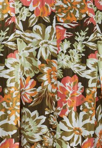 Bloemmotief op stof met grote witte, roze en oranje bloemen tegen een bruine achtergrond, met groene bladeren doorheen verspreid.