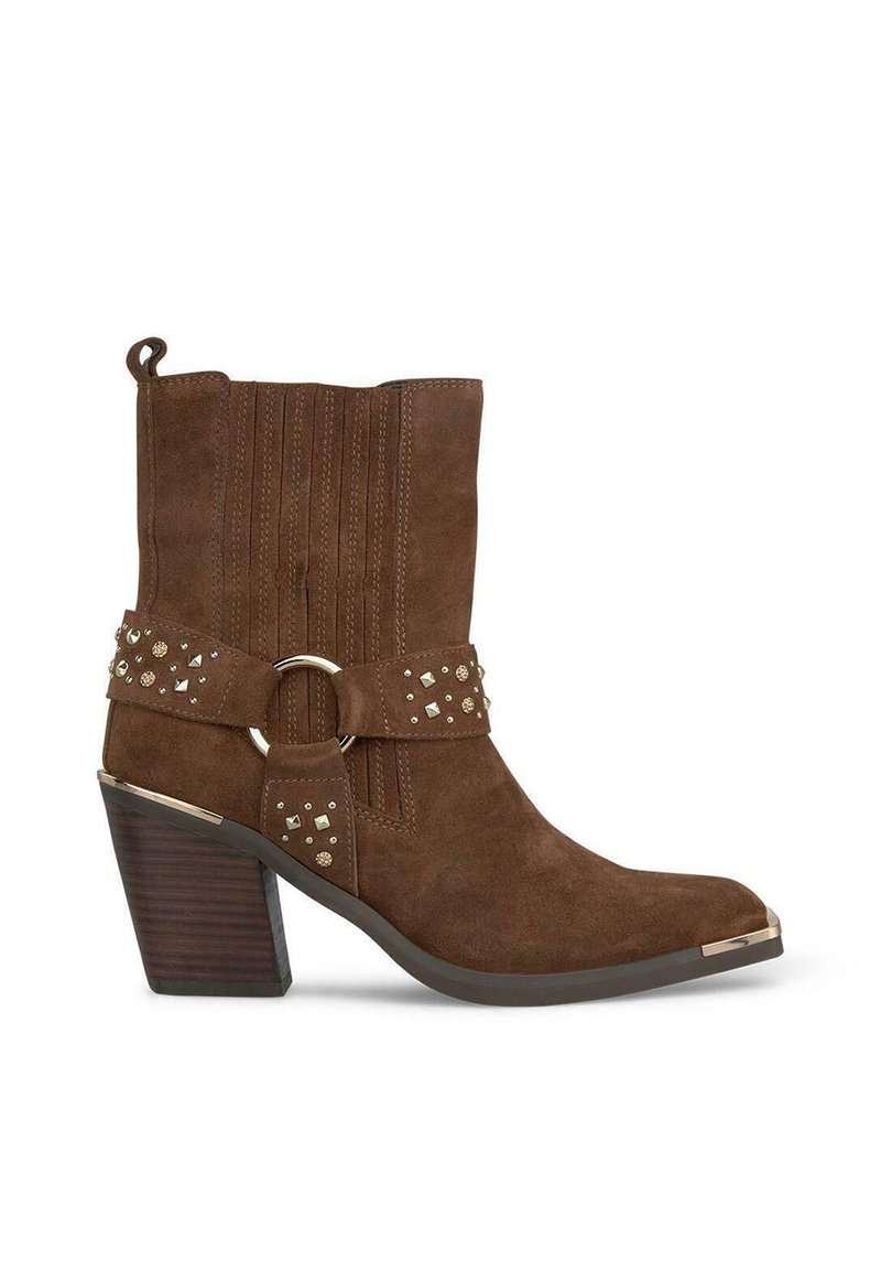 Bottines en daim marron avec un bout pointu, des sangles décoratives, des clous et un talon épais au texture boisée. Présente des coutures verticales.