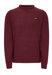 Bordeauxroter Strickpullover mit Rundhalsausschnitt, strukturiertem Muster und gerippten Bündchen. Mit einem kleinen gelb-grünen Emblem auf der Brust.