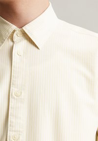 Lichtgele gestreepte shirt met een button-down kraag, met een gladde textuur en vijf knopen aan de voorkant. Schoon, casual ontwerp.