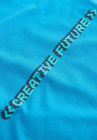 Bright blue fabric with the phrase "CREATIVE FUTURE" in large pixelated font diagonally across.