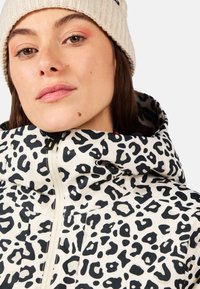 Kurtka w wzór panterki z wysokim kołnierzem, czarno-biały wzór, z zapięciem na zamek błyskawiczny i eleganckim krojem. Miękka, gładka tekstura z nowoczesnym fasonem.