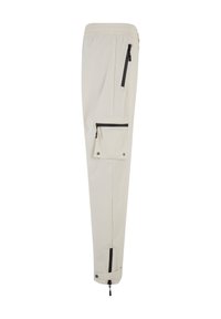 Pantaloni cargo beige chiaro con vita elastica, numerose tasche con zip e polsini regolabili, caratterizzati da dettagli neri e accessori metallici.