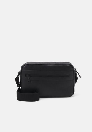 Sort rektangulært crossbody-taske med frontlynlåslomme og justerbar stofrem på en ensfarvet baggrund.