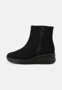 Stivale alla caviglia nero in tessuto elasticizzato, con zip laterale, suola a zeppa e texture liscia. Silhouette elegante e design minimal.