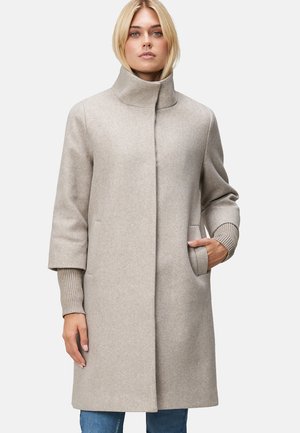 Manteau en laine beige clair avec un col haut, des manches larges et des poignets en tricot côtelé. Il dispose de poches latérales et d'une silhouette droite.